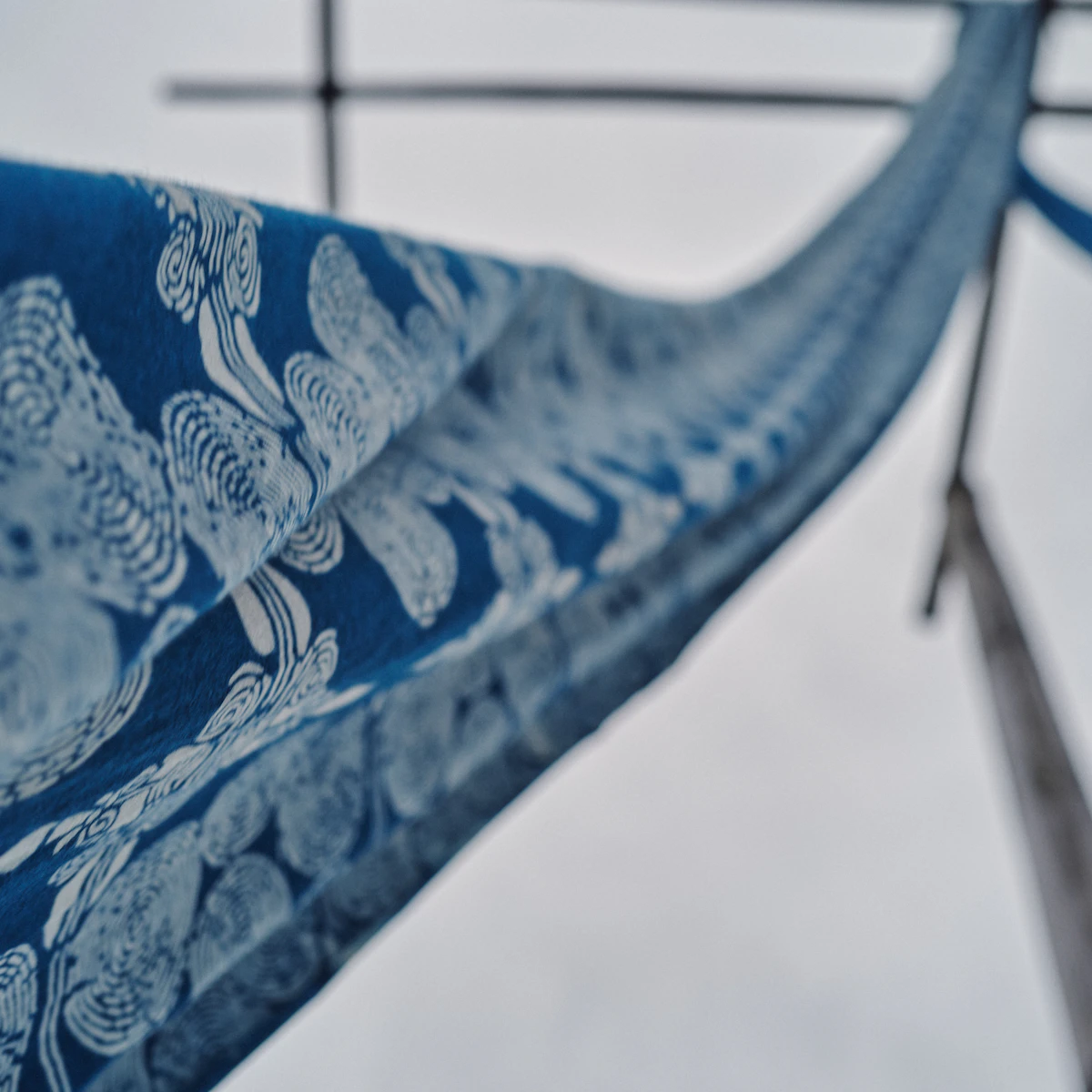 A close-up of indigo and rust Sumbanese ikat cloth laid on raw stone.