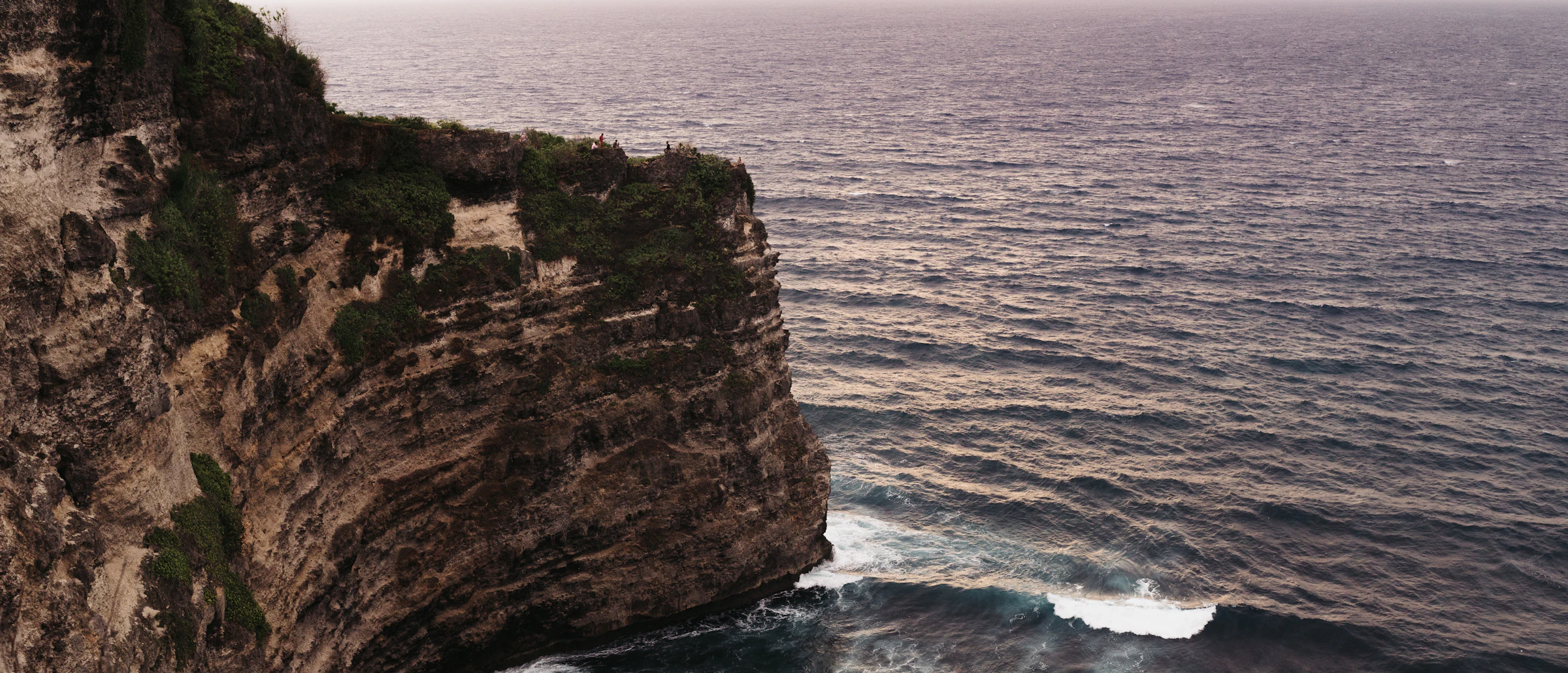 The main pavilion of Marapu Cliff at dusk, its infinity pool meeting the Indian Ocean below.