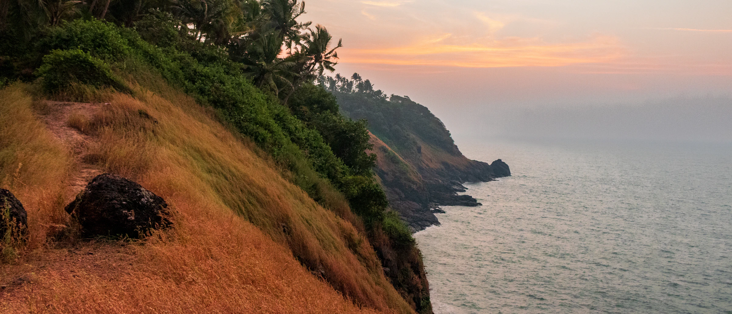 Golden savannah hills meeting turquoise water and an empty white beach in Sumba.